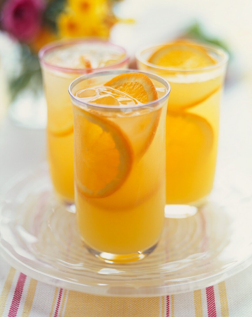 Three Glasses of Sparkling Orangeade with Orange Slice Garnishes