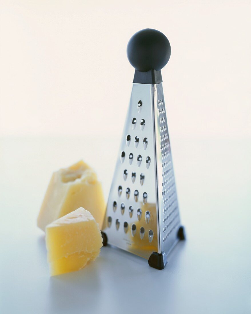 Two Chunks of Parmesan Cheese with a Box Grater
