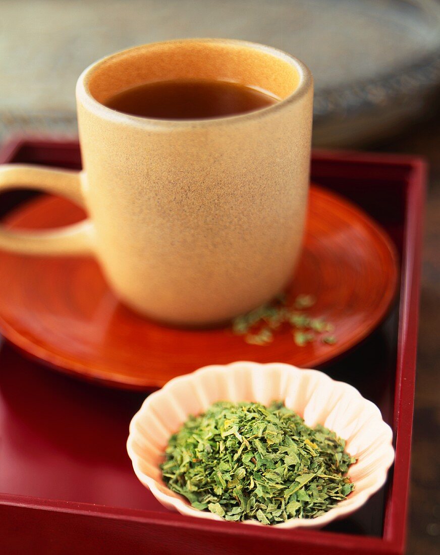 Eine Tasse Brennesseltee und getrocknete Teeblätter