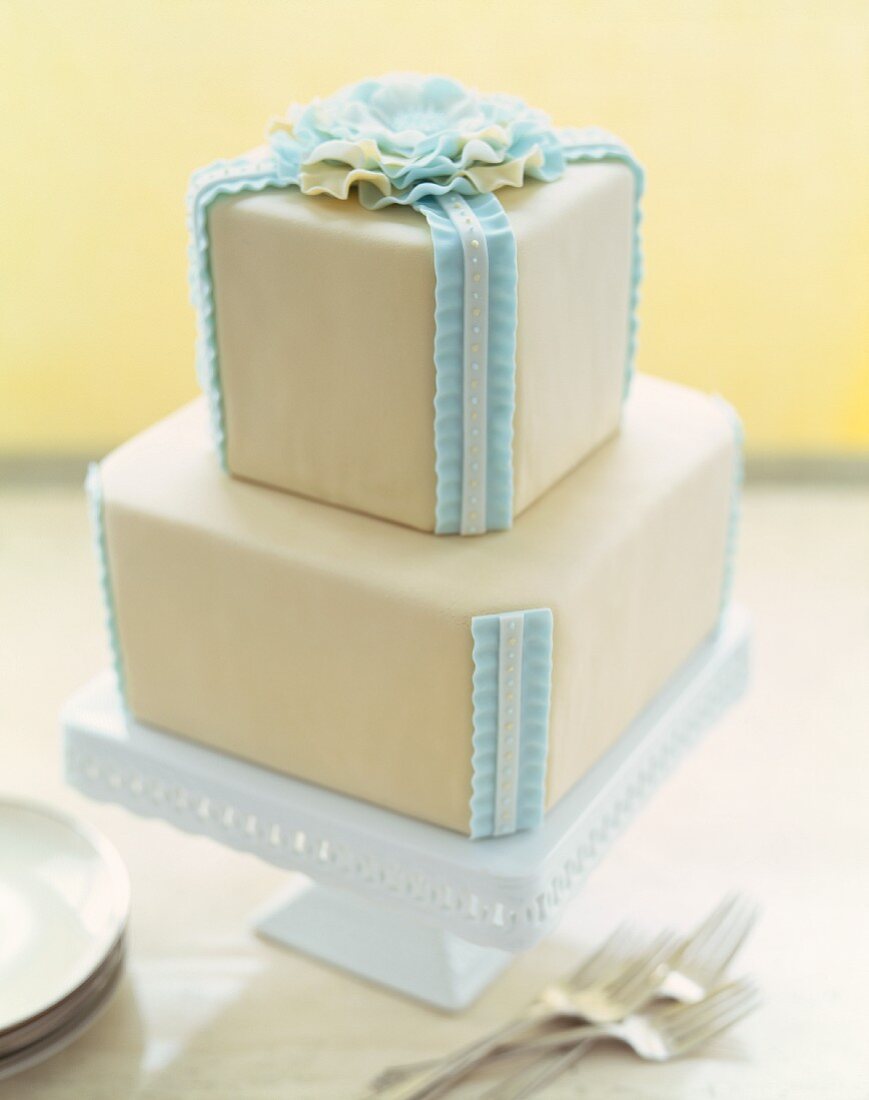 Two Tiered Cake with Blue Frosting Ribbons and Flower; On Cake Plate