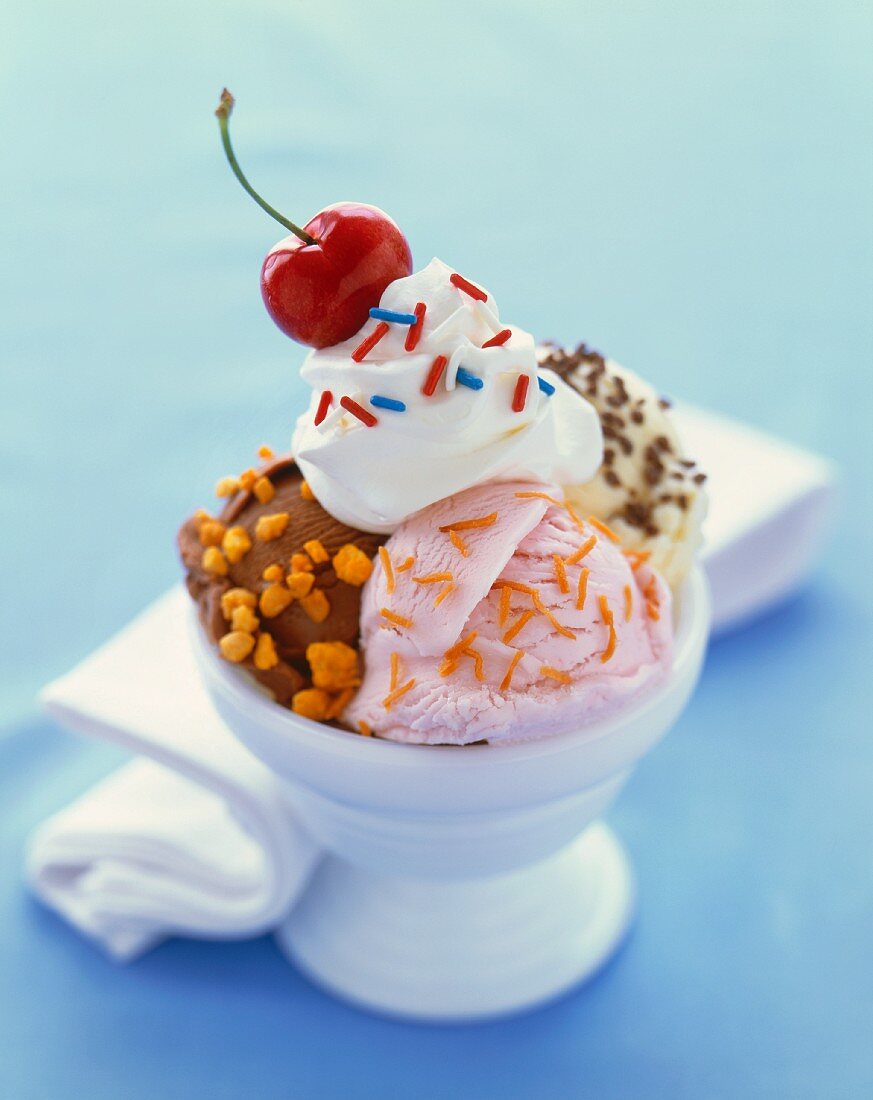 Eisbecher mit Sahne, Zuckerstreuseln und Kirsche