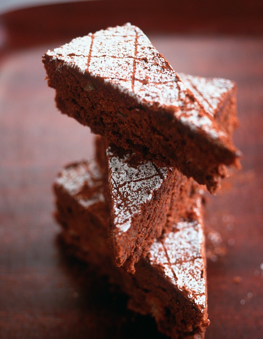 Drei Stücke Schokoladenkuchen mit Puderzucker, gestapelt