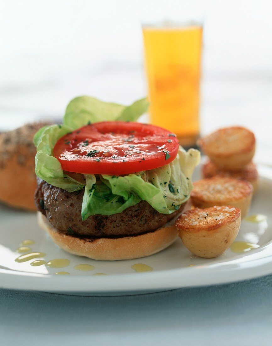 A hamburger with lettuce and tomatoes, roast potatoes and beer