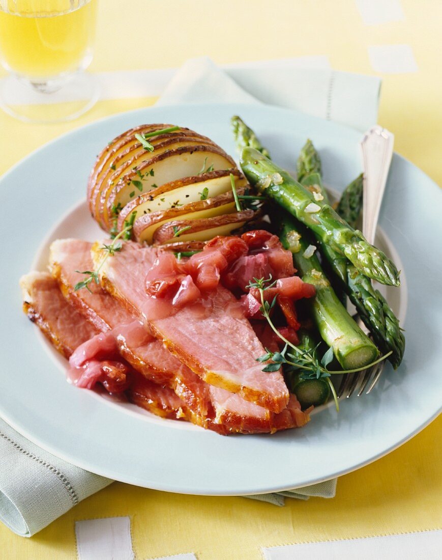 Roast ham with green asparagus a baked potato