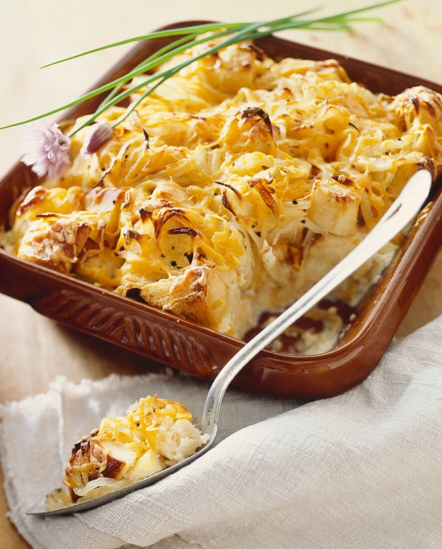 Savory Bread Pudding with Onions and Cheese; In Baking Dish with Scoop Removed