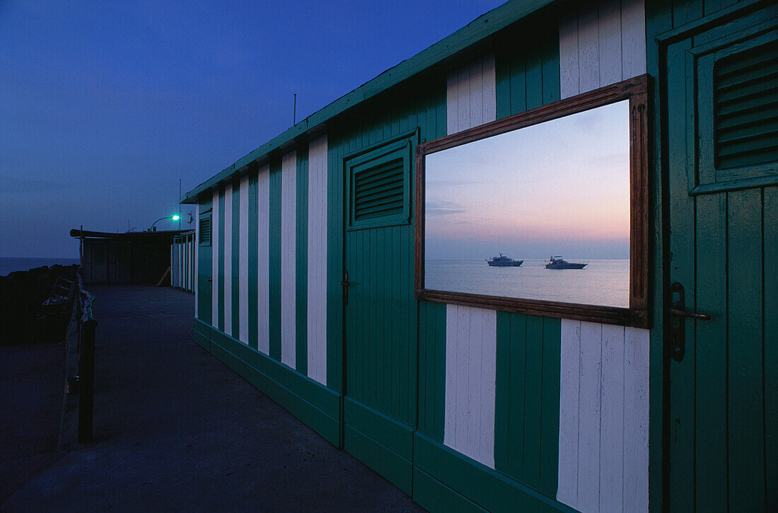 Mirror at bathhouse wall reflecting the sunset, Capri, Italy