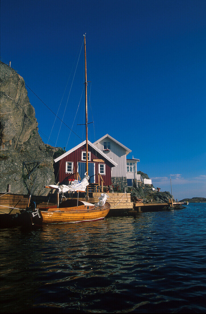 Wohnhaus und Boot an der Küste unter blauem Himmel, Schweden, Europa