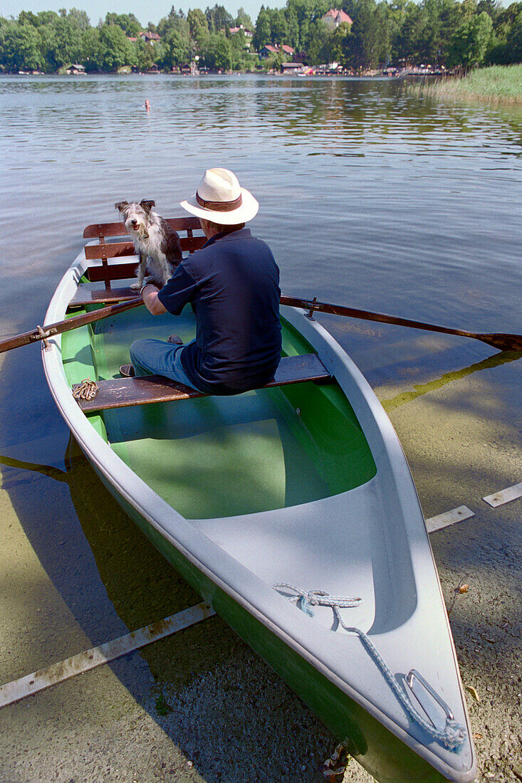 Mann mit Hund in Ruderboot, Staffelsee, Bayern, Deutschland