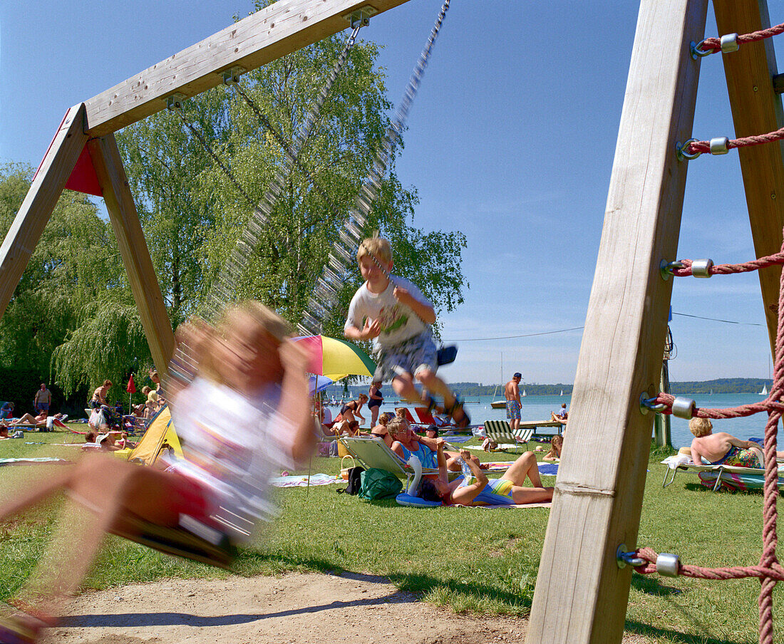 Swinging children on lake, Woerthsee, Bavaria, Germany