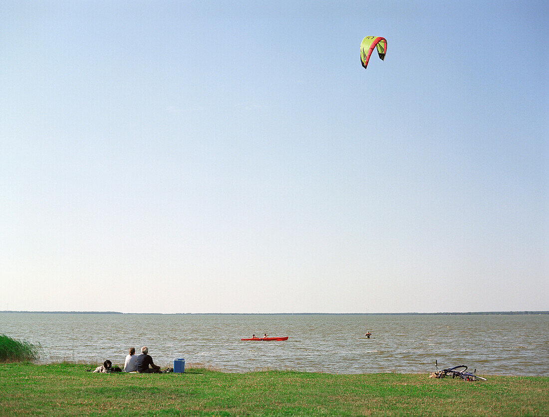 Two people watching to canoe and kite, Neuendorf, Saaler Bodden, Fischland-Darss-Zingst Mecklenburg-Western Pomerania, Germany
