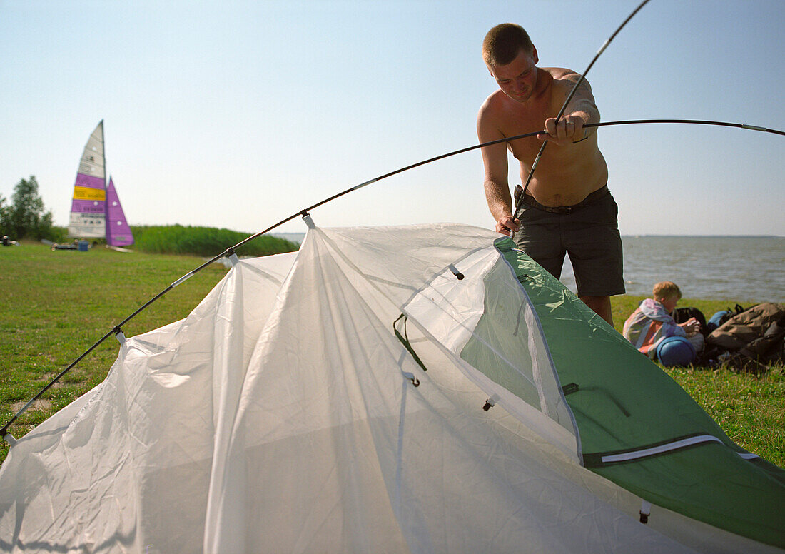 Man pitching a tent, Neuendorf, Fischland-Darss-Zingst, Mecklenburg-Western Pomerania, Germany