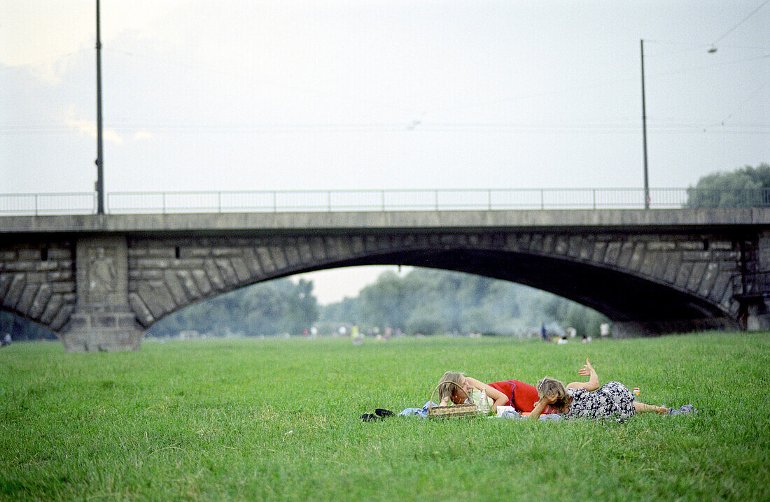 Zwei Frauen liegen auf der Wiese der Isarauen, München, Bayern, Deutschland, Europa