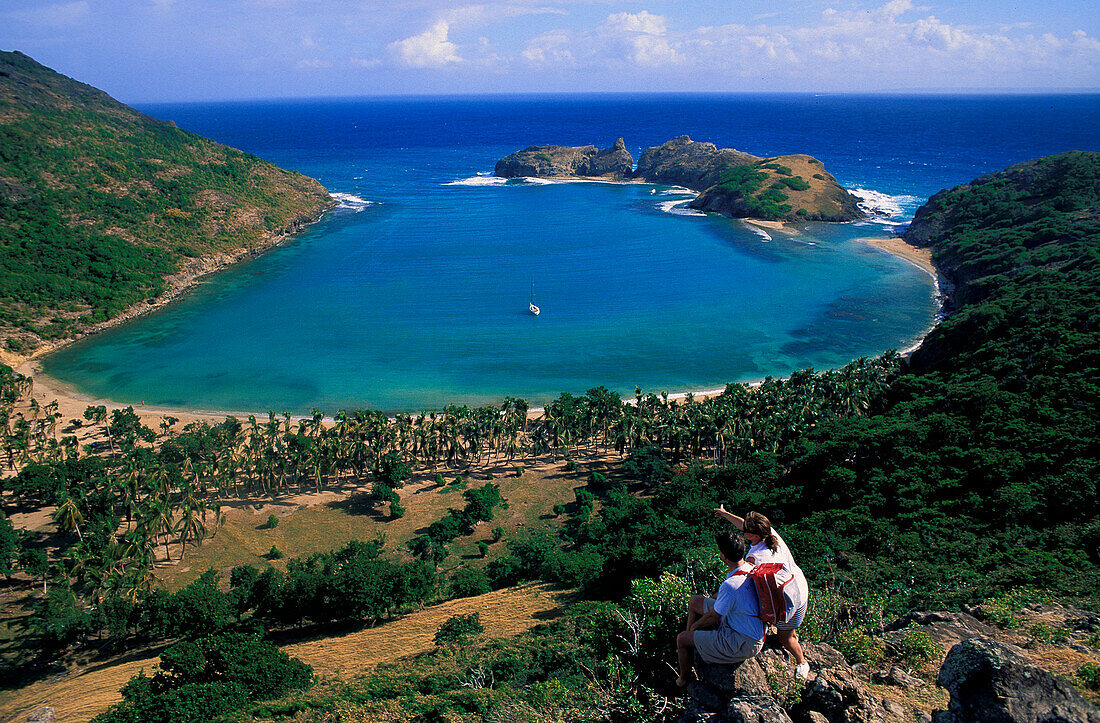 Hikers looking at boats in bay, Iles des Saintes, Guadeloupe, Caribbean, America