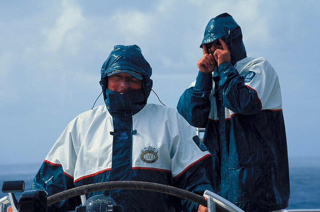 Männer in Regenjacken am Steuerrad eines Segelboots, Karibik, Amerika