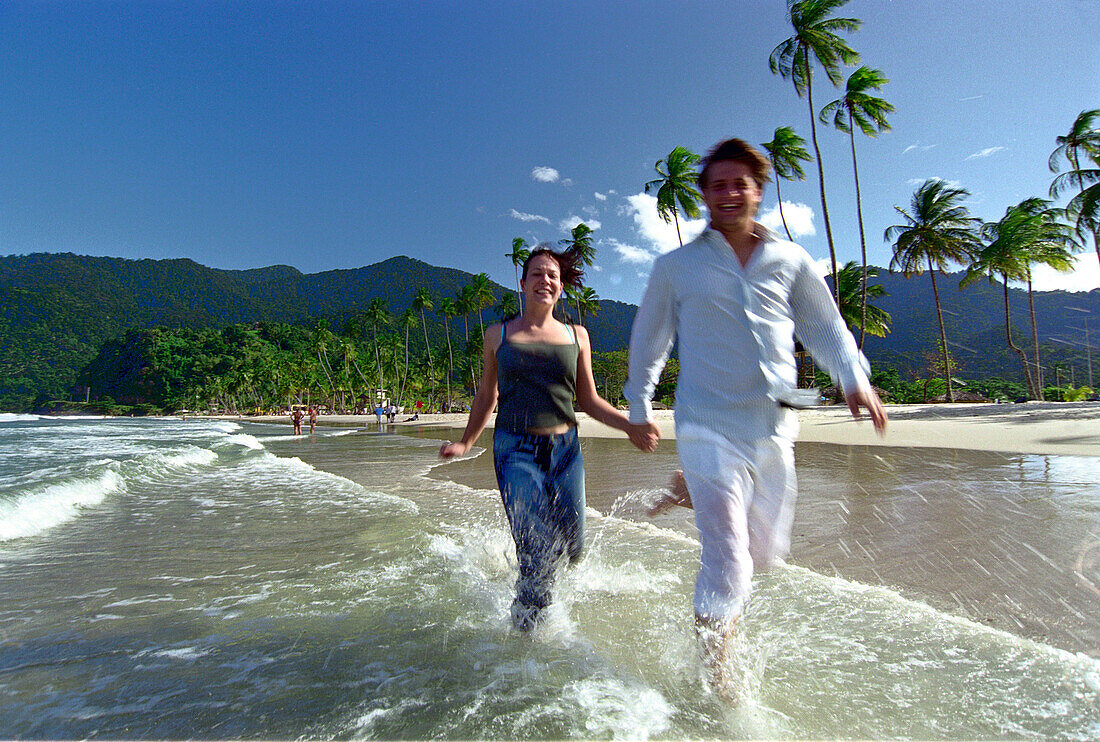 Young couple running hand in hand on the waterfront, Maracas Bay, Trinidad, Caribbean, America