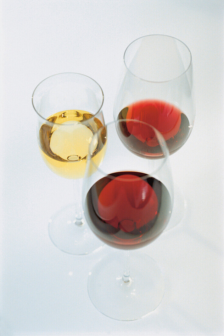 Three glasses of wine, two with red wine and one glass with white wine