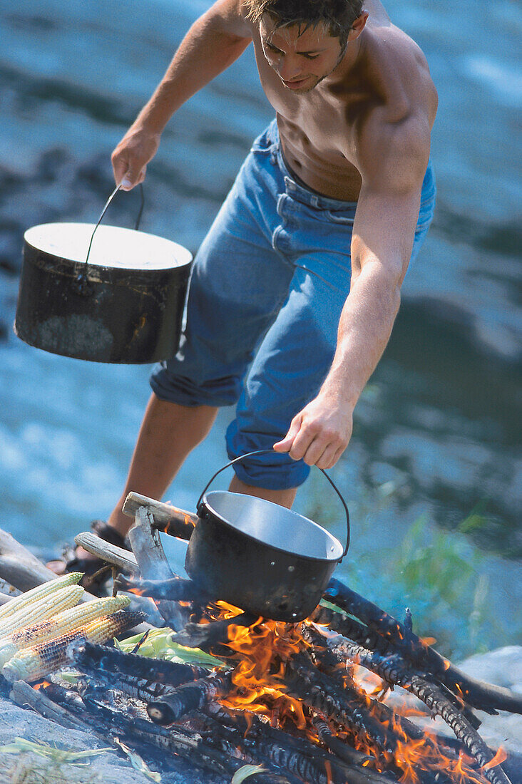 Mann beim Kochen in der Wildnis, Oberbayern, Deutschland