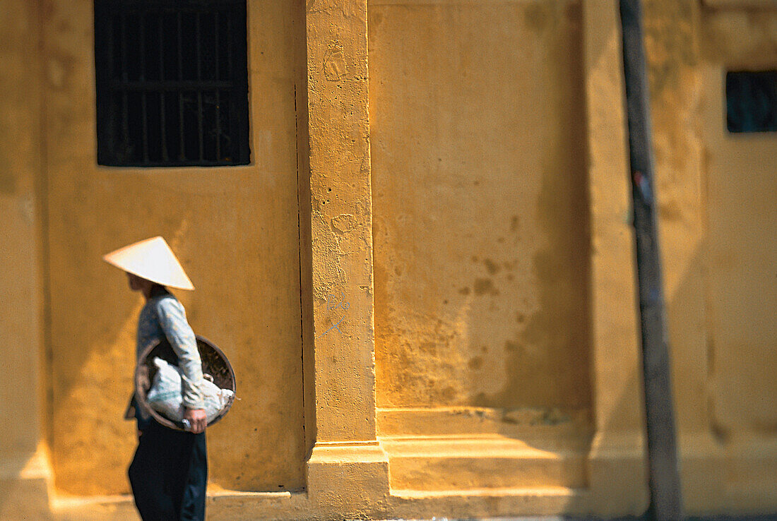 Frau mit Strohhut läuft eine Strasse entlang, Vietnam, Asien