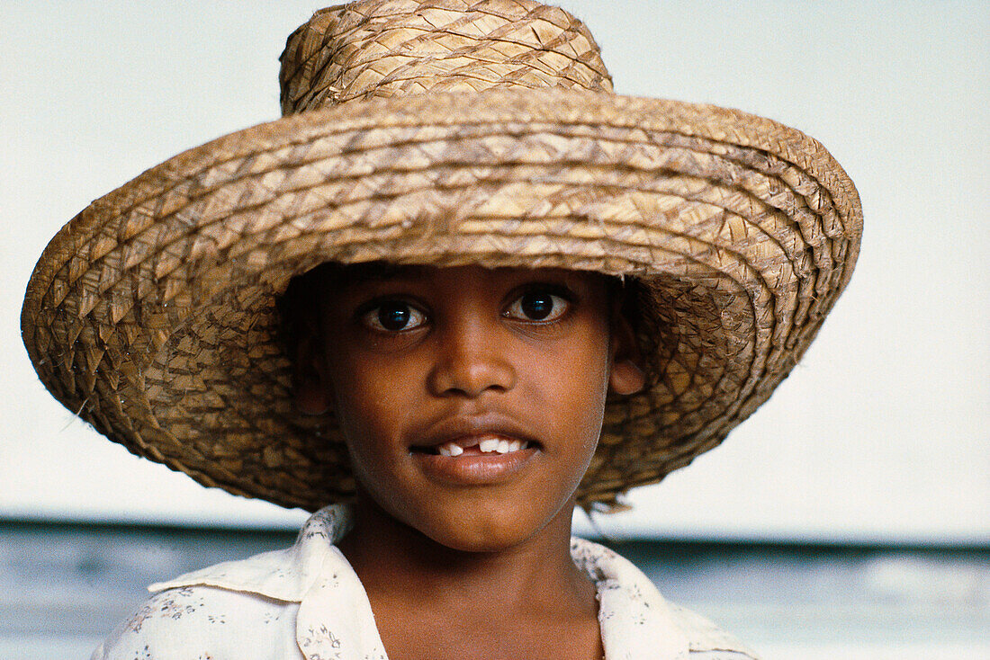 Portrait of a boy with tooth gap and a straw hat, Guadeloupe, Caribbean