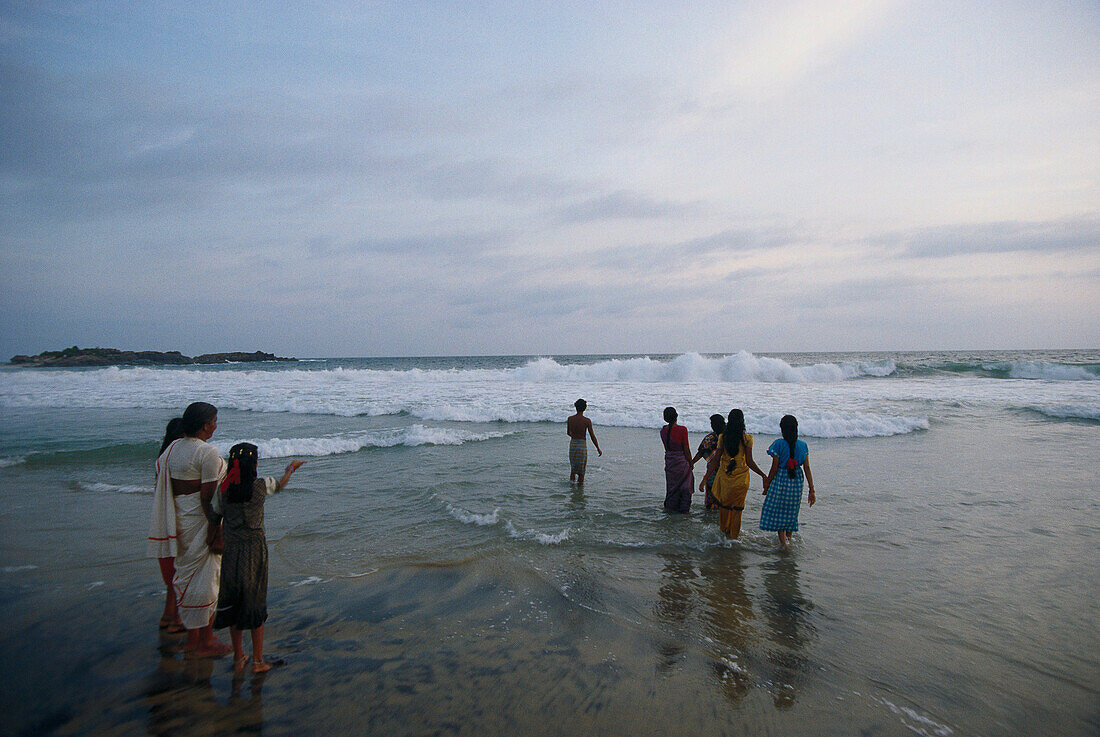 Frauen stehen am Strand im flachen Wasser, Kovalam Beach, Kerala, Indien