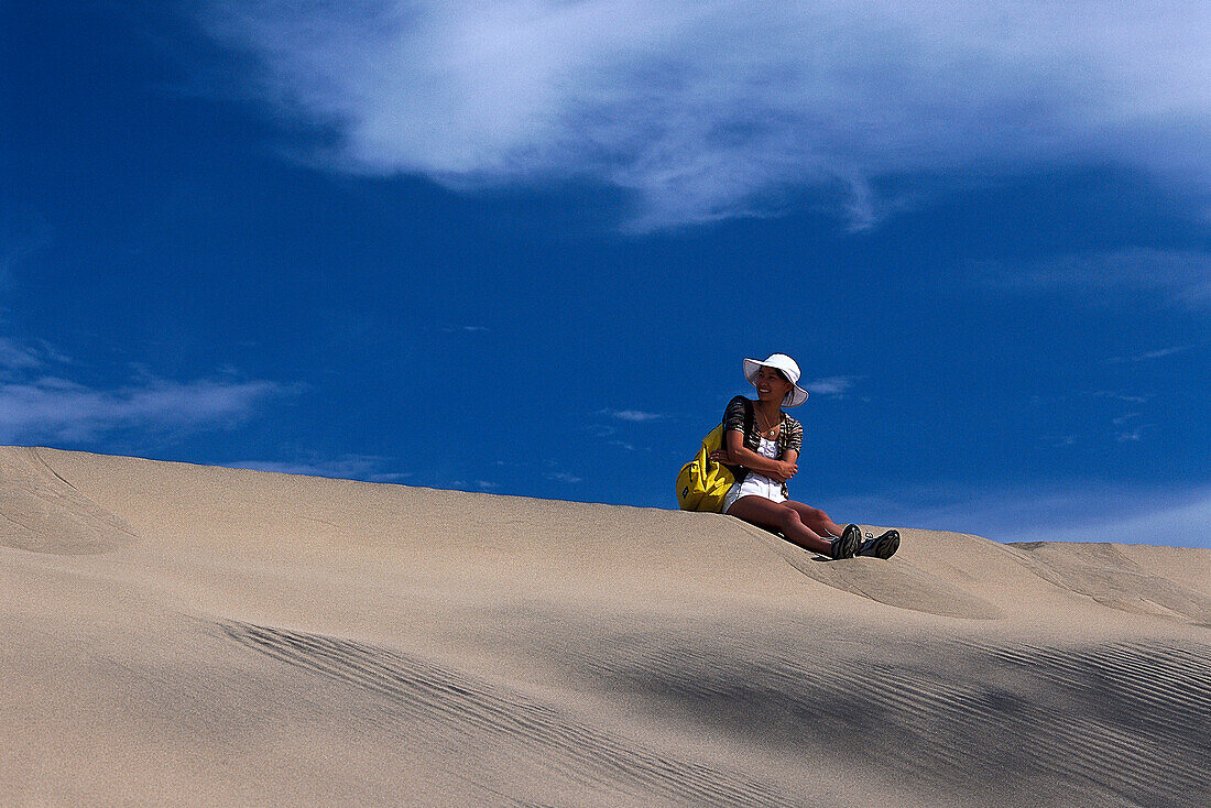 Frau sitzt an den Dünen, Playa del Ingles, Maspalomas Gran Canaria, Kanarische Inseln, Spanien