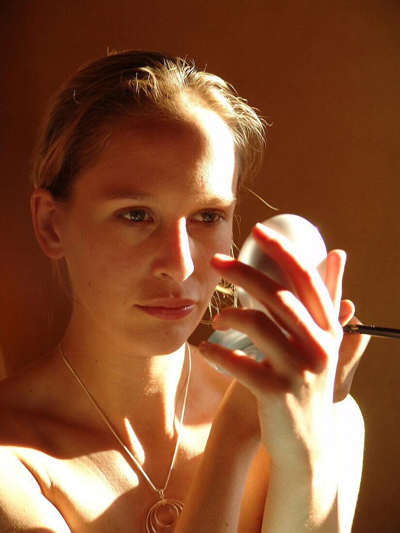 Young woman putting on make-up