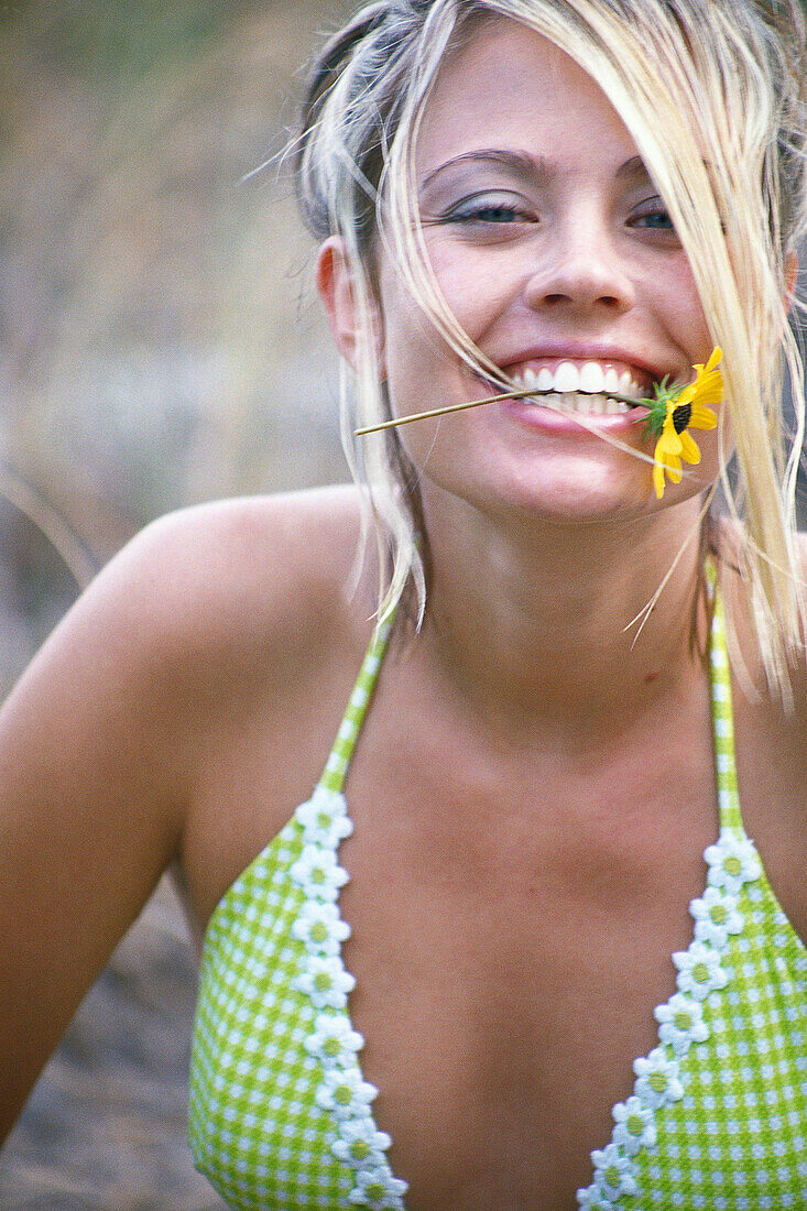 Portrait of young woman with flower in mouth