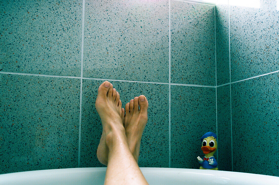 Feet lying on the brim of the bathtub