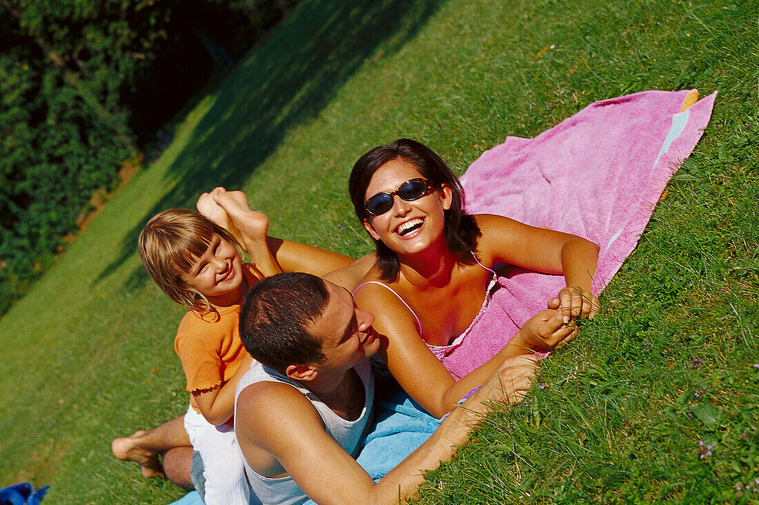  David Sinar and his family are lying on a blanket in the park, smiling and laughing.