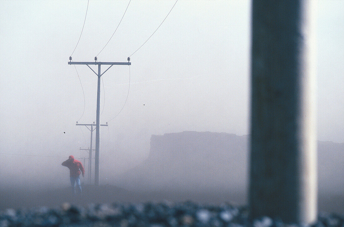 Fussgänger schützt das Gesicht vor einem Sandsturm, island