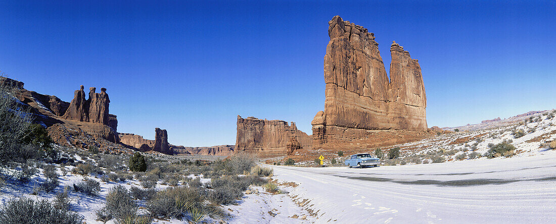 Ein Auto fährt durch den einsamen Arches Nationalpark, Moab, Utah, USA