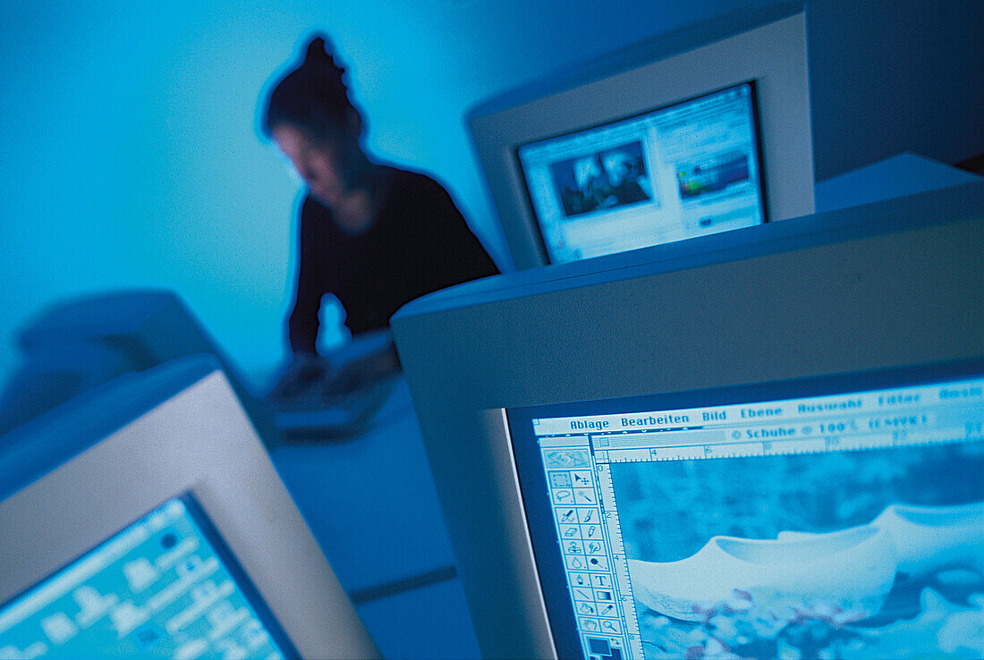 Woman using personal computer sitting behind screens in an office