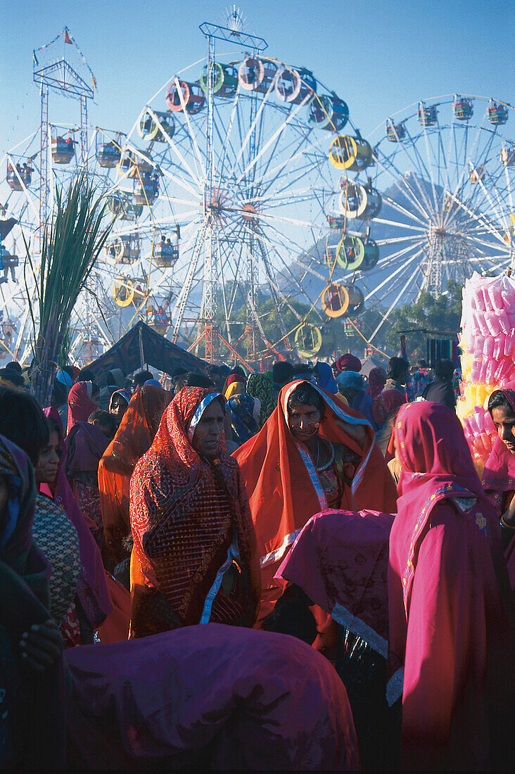Frauen in Saris und Riesenräder im Sonnenlicht, Kamelmarkt, Pushkar, Rajasthan, Indien