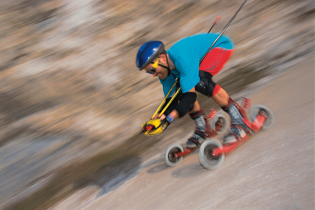 Mann auf Mountainskates fährt einen Abhang hinunter, Österreich, Europa