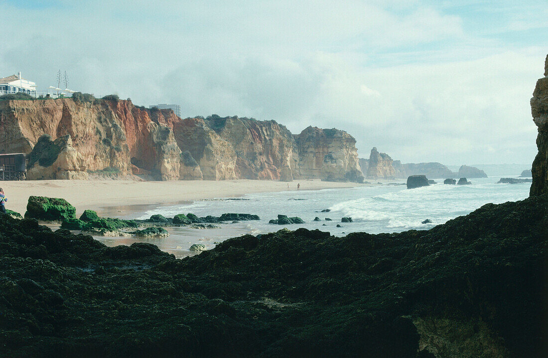 Strand und steile Felsen unter dichten Wolken, Praia de Rocha, Portimao, Algarve, Portugal