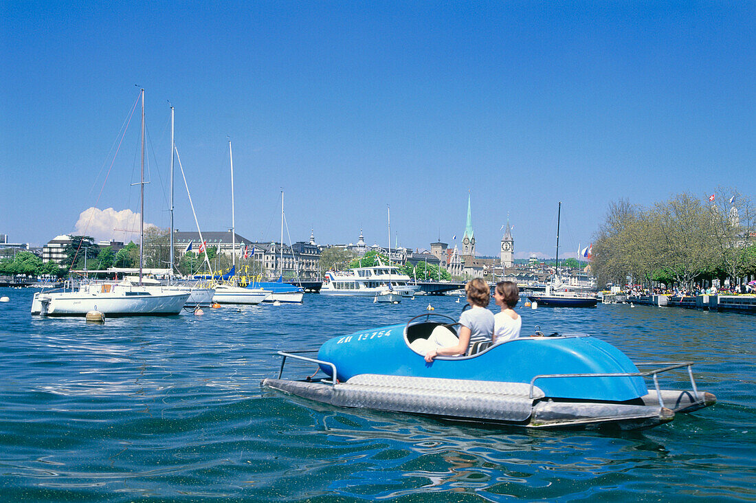 Menschen fahren in einem Tretboot auf dem Zürichsee mit Blick auf die Stadt, Zürich, Schweiz