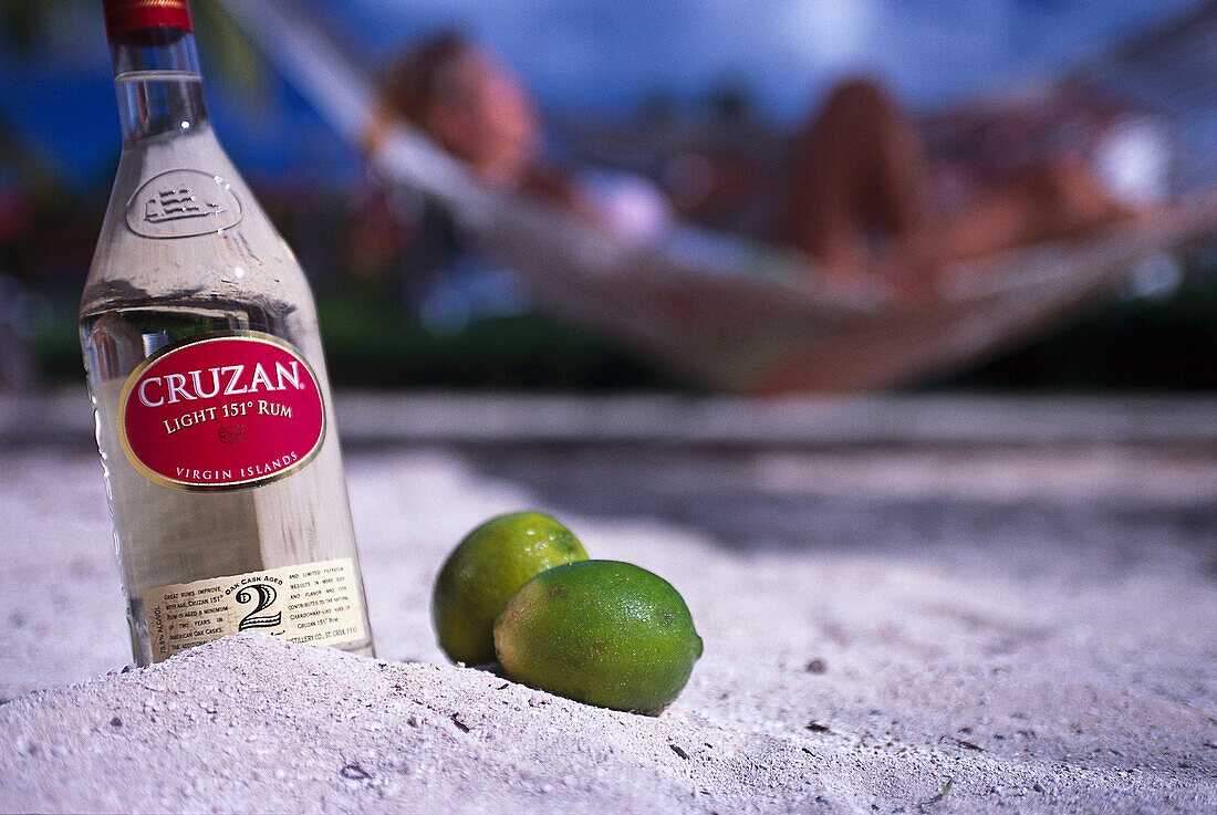 Bottle of rum and limes in the sand, St.Thomas, Jamaica, Caribbean, America