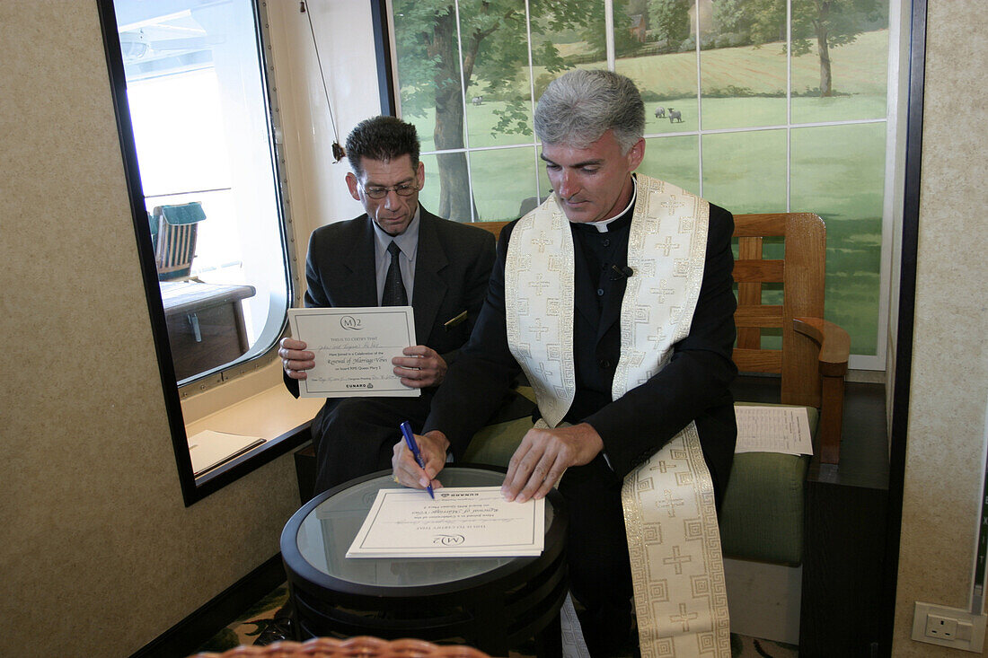 Queen Mary 2, Ship priest reverend Dr.Karl Rodig, Queen Mary 2, QM2 Bordpriester Reverend Dr.Karl Rodig unterschreibt Urkunden für Ehepaare, die in Kürze an einer Wedding Renawal Zeremonie teilnehmen werden.