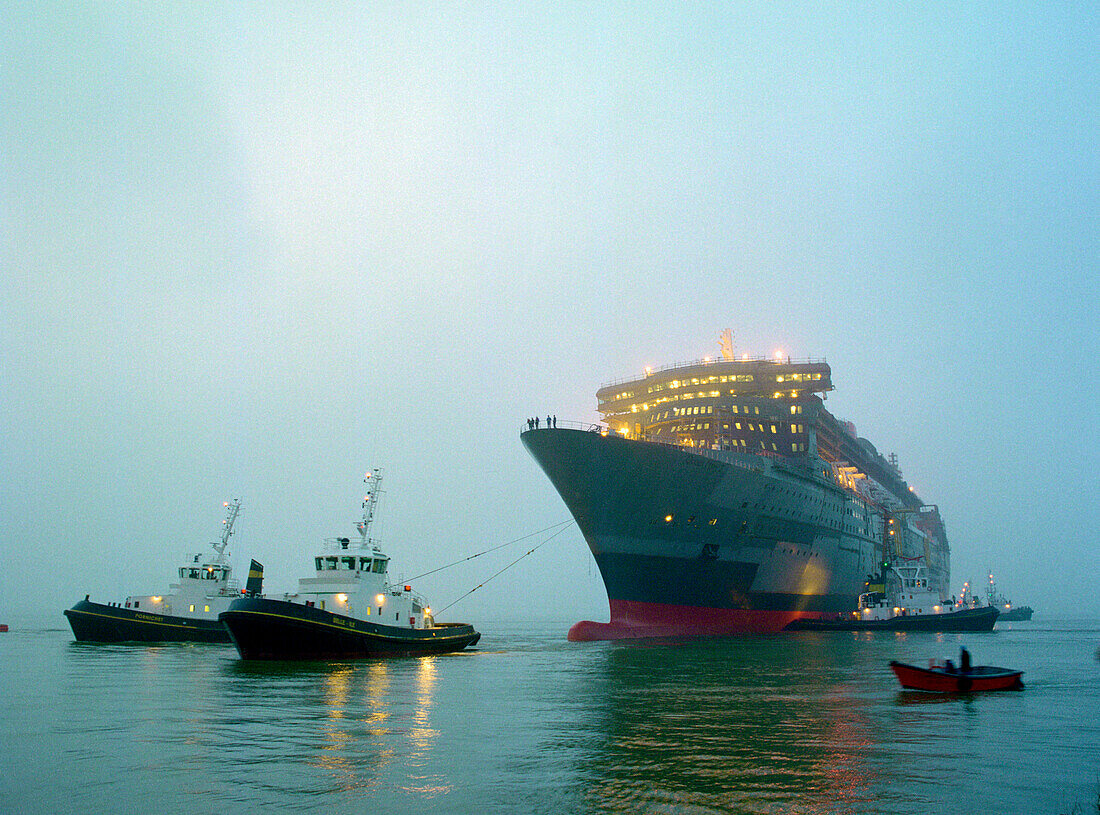 Schlepper ziehen das Kreuzfahrtschiff Queen Mary 2 im Morgengrauen, Saint-Nazaire, Frankreich