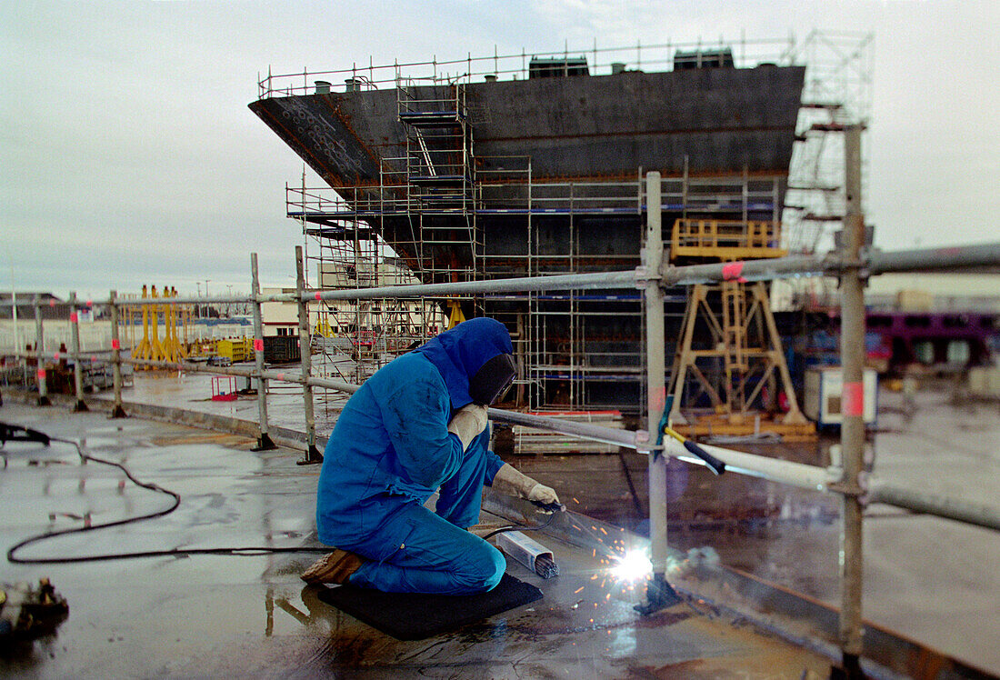 Worker welding steel plates, dry dock, Queen Mary 2, Saint-Nazaire, France