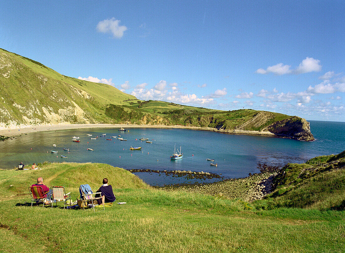 Trippers relaxing on the seaside, Lulworth Cove, South, England Great Britain