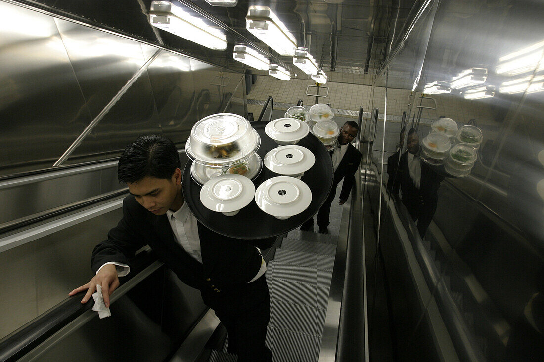 Queen Mary 2, Waiter on a escalator, Queen Mary 2, QM2 Kellner holen ihre bestellten Gerichte in der Hauptküche ab, Rolltreppe aus der Küche zum oberen Teil des Britannia Restaurants. Buch S. 149
