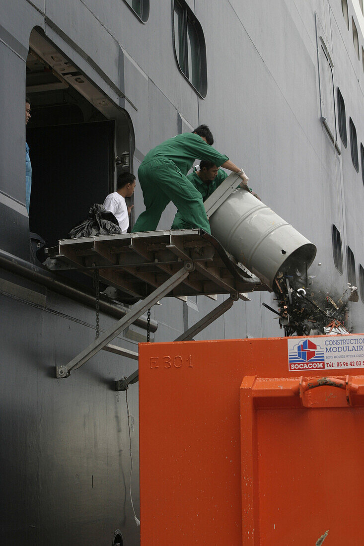 Queen Mary 2, Waste disposal, Queen Mary 2, QM2 Anleger für Kreuzfahrtschiffe im Hafen von Fort de France, Martinique Besatzungsangehörige werfen Müll über Bord in einen Container.