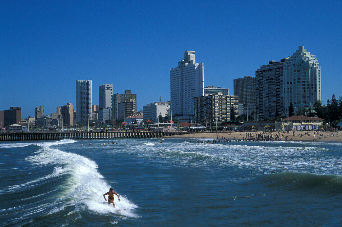 Surfer in the surge in front of the skyline of Durban, Golden Mile, Durban, South Africa, Africa