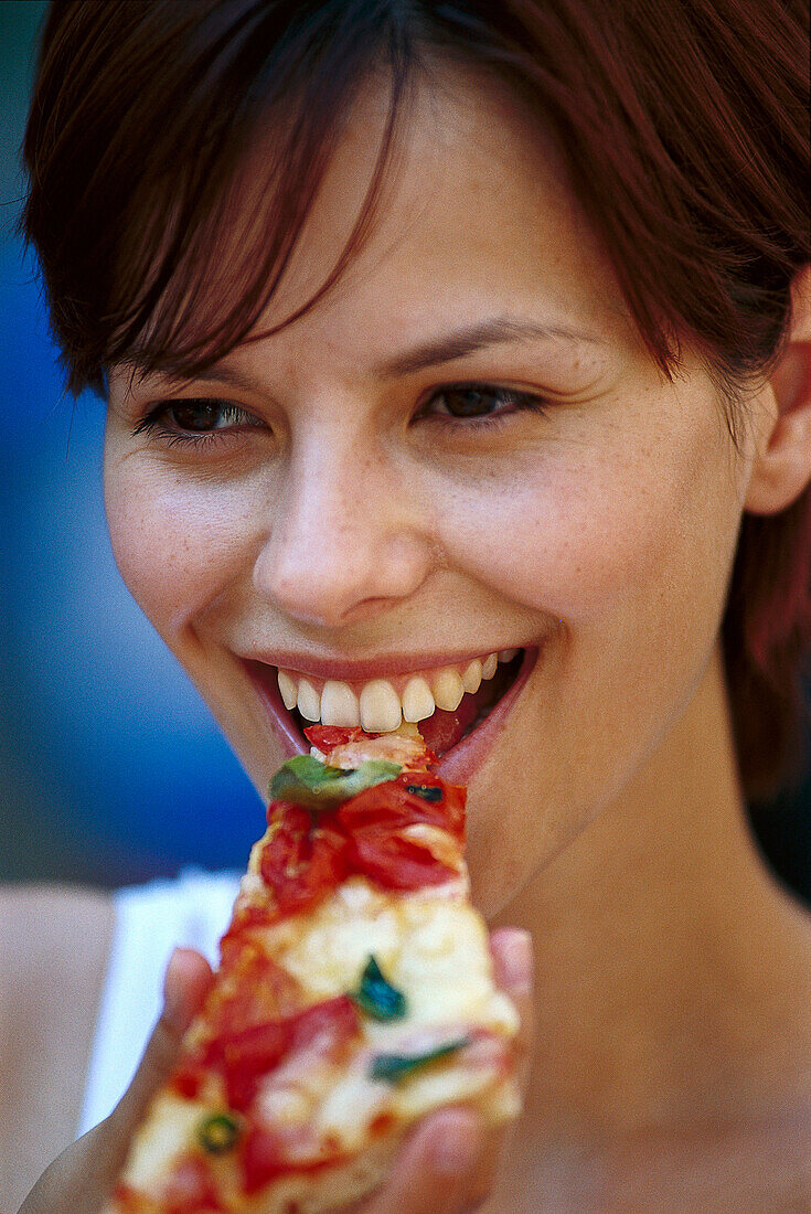 Young woman eating a piece of pizza, Italy, Europe