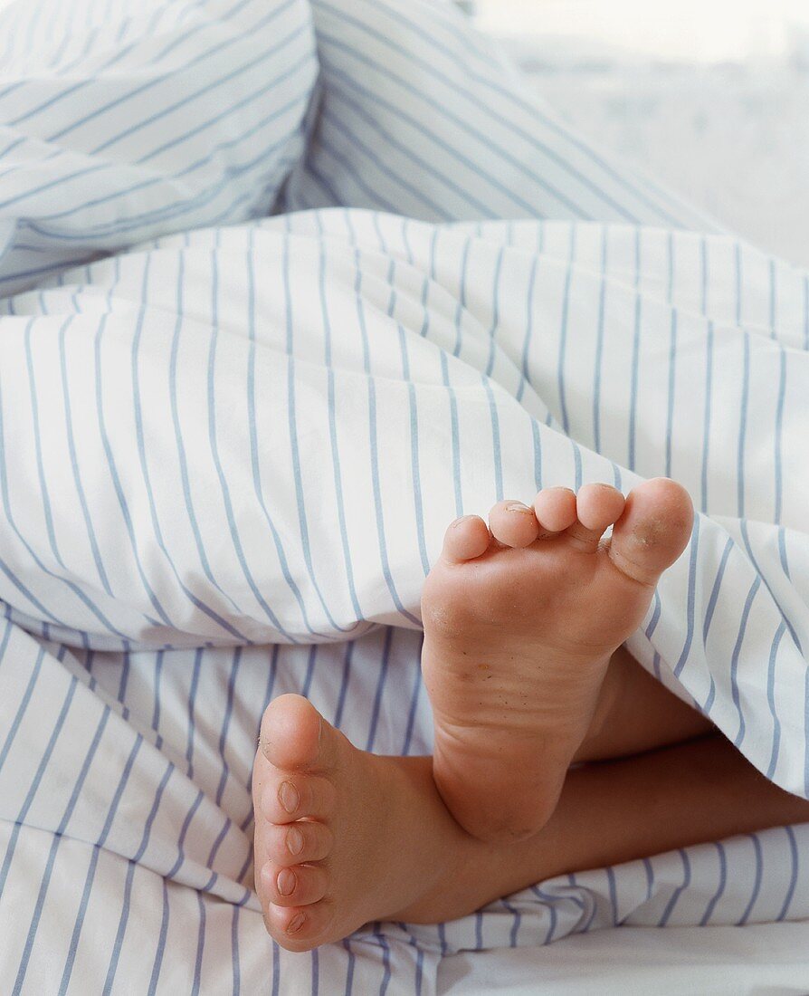 A child's feet sticking out of a duvet