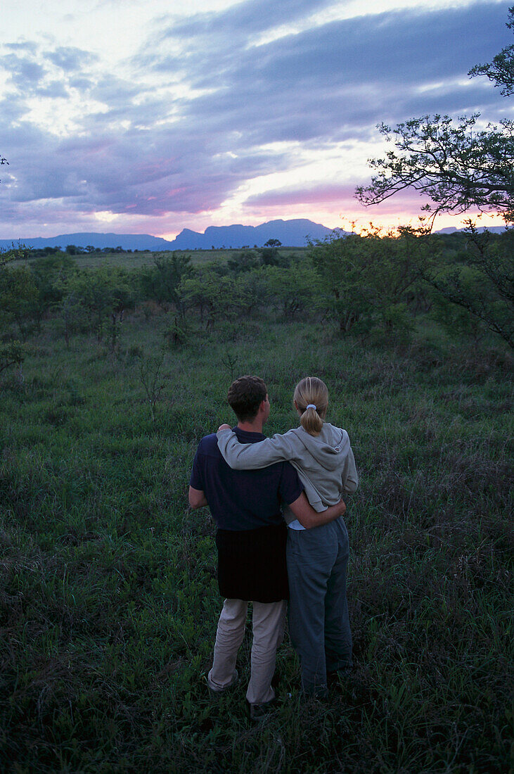 Paar betrachtet Sonnenuntergang, Blick auf die Drakensberge, Krüger NP, Südafrika
