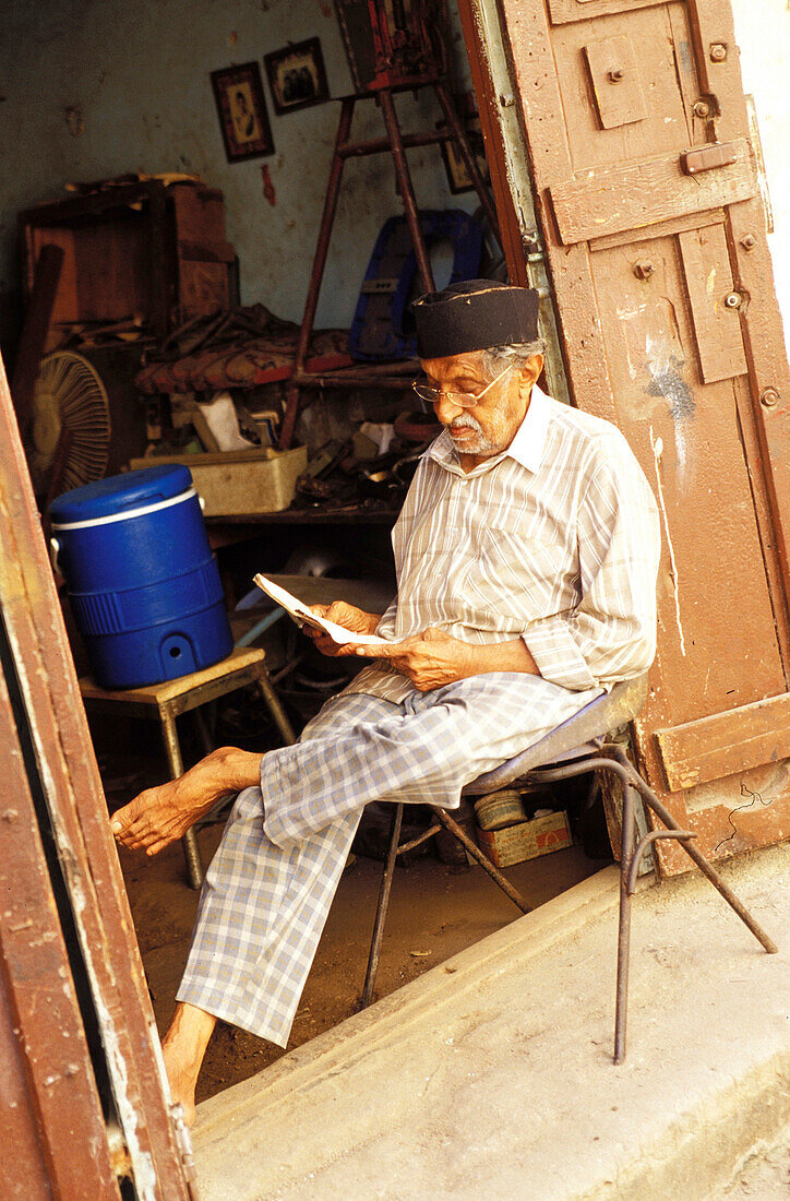 Old man reading, people in shop