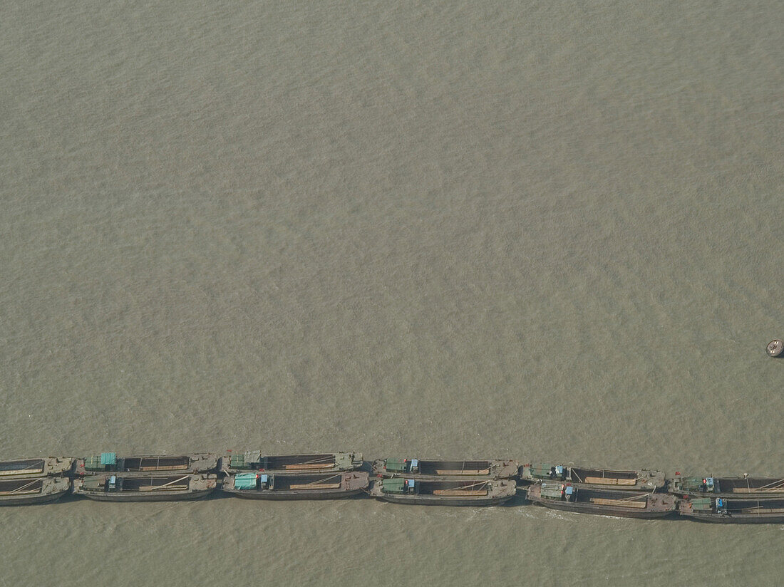 Eine Reihe Boote auf einem schlammigen Fluss, Shanghai, China