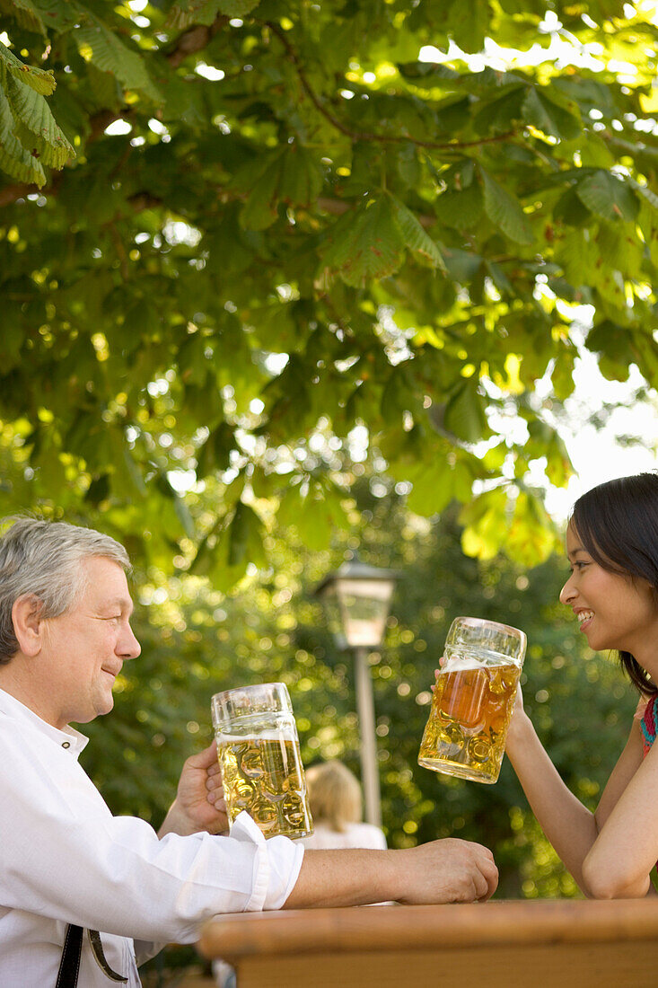 Man and young woman in beer garden, Lake Starnberg, Bavaria, Germany